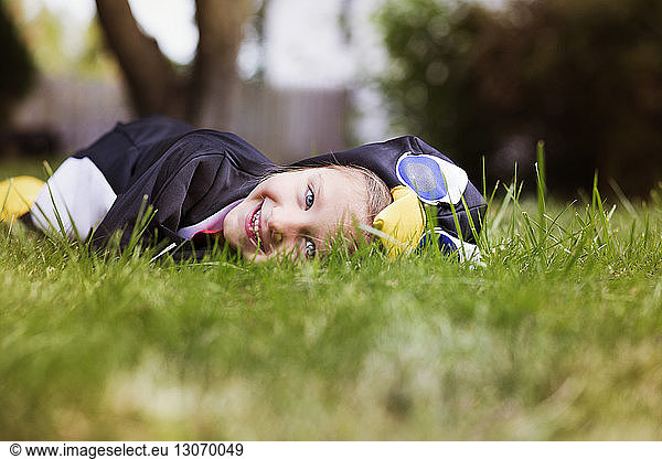 Portrait of smiling girl in Halloween costume lying on lawn