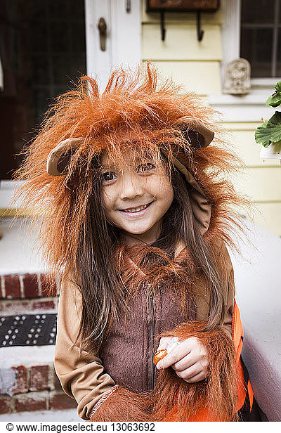 Portrait of smiling girl in Halloween costume standing against house