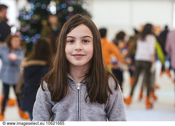Portrait of smiling girl on ice rink at Christmas time