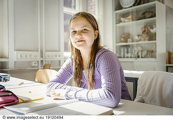 Portrait of smiling girl sitting at desk in classroom