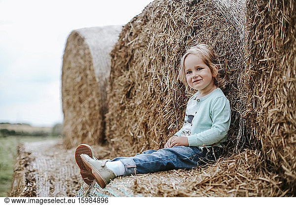 Portrait of smiling girl sitting on straw bales