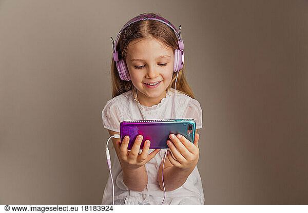Portrait of smiling girl watching movie with smartphone and headphones