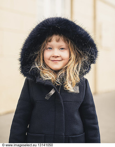 Portrait of smiling girl wearing fur coat while standing outdoors