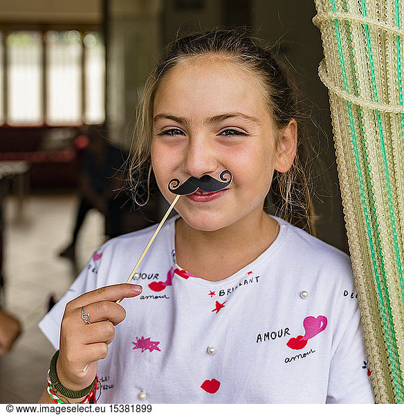 Portrait of smiling girl with toy moustache