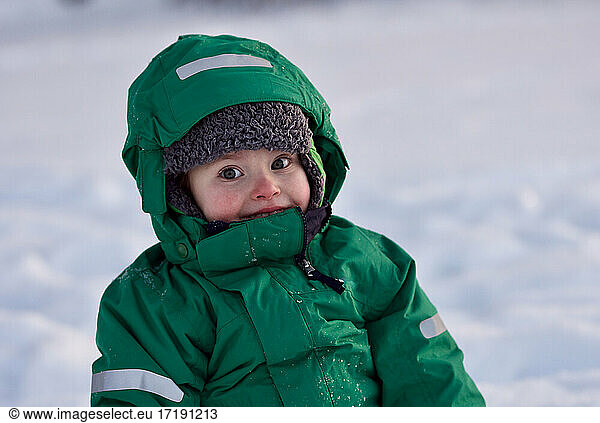 Portrait of smiling little boy playing in snow on cold winter day