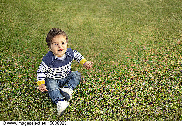 Portrait of smiling little boy sitting on lawn