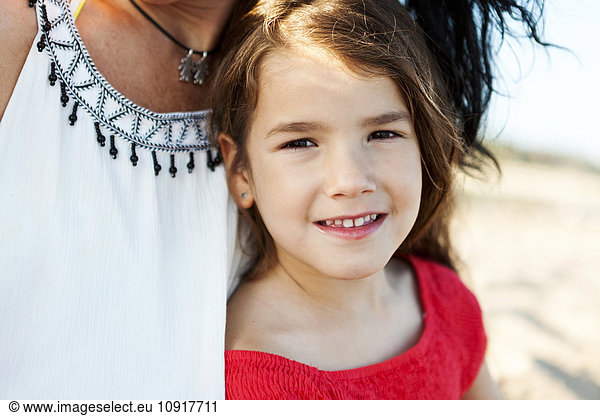 Portrait of smiling little girl besides her mother on the beach