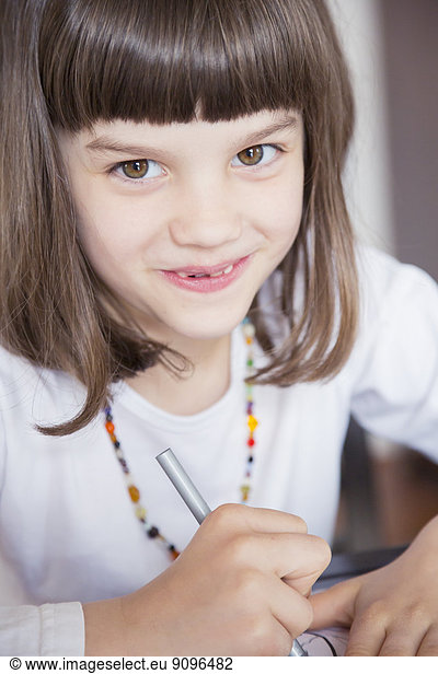 Portrait of smiling little girl painting with wax crayon