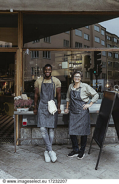 Portrait of smiling male and female employee outside delicatessen shop