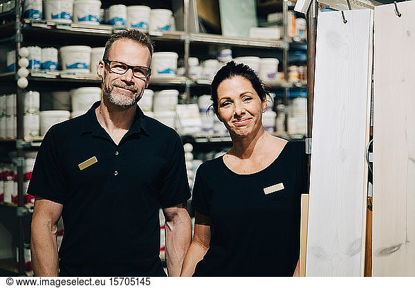 Portrait of smiling male and female employees standing in storage room