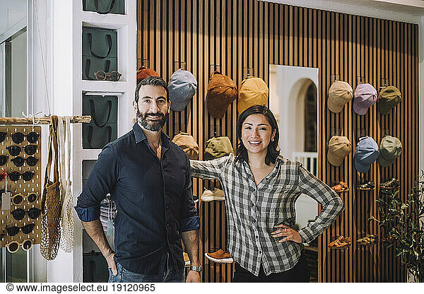 Portrait of smiling male and female sales colleagues standing together at fashion store