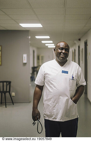 Portrait of smiling male doctor walking in hospital corridor