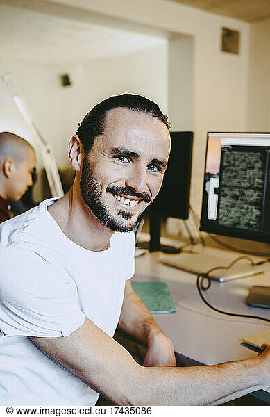 Portrait of smiling male hacker at startup at desk company