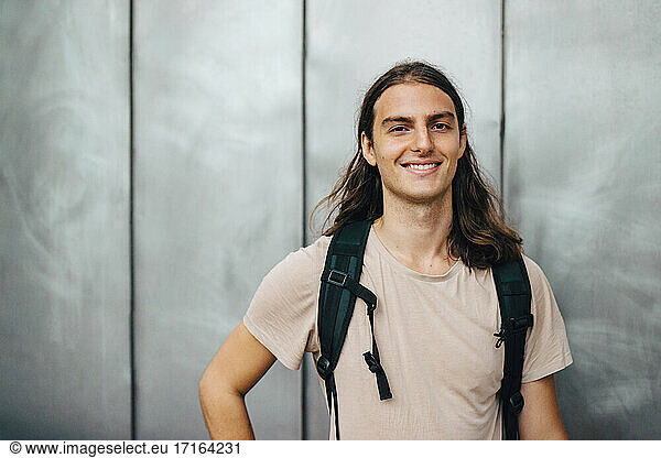 Portrait of smiling male student against gray wall