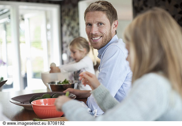 Portrait of smiling man cooking food with daughters in kitchen