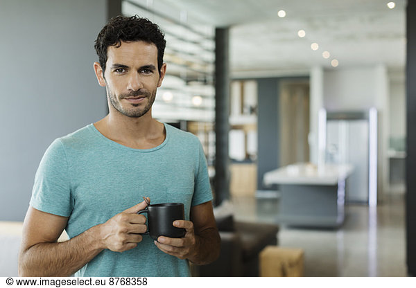 Portrait of smiling man drinking coffee at home