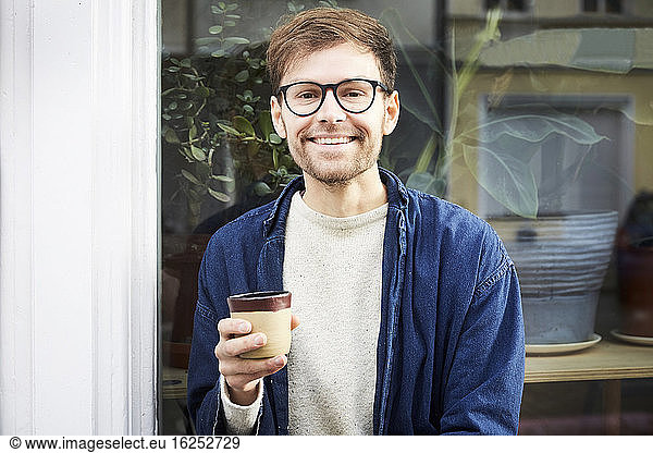 Portrait of smiling man having coffee outside art studio