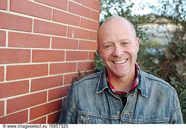 Portrait of smiling man in front of brick wall sunny day in California