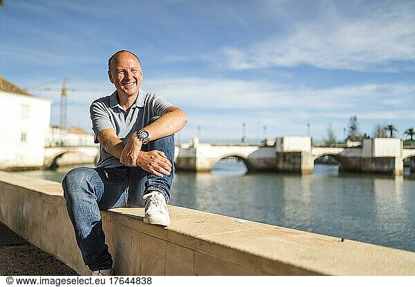 Portrait of smiling man relaxing by the riverbank in touristic and historic Tavira  Algarve  Portugal  Europe