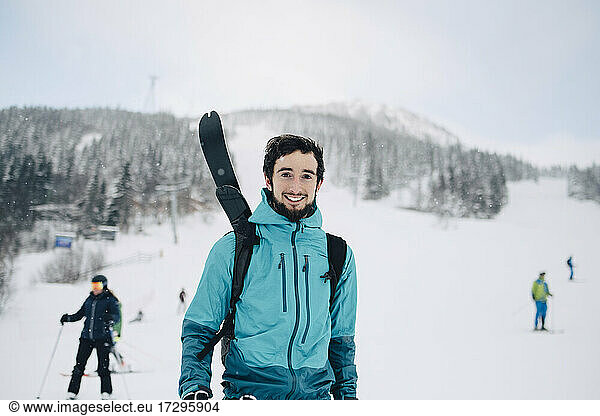 Portrait of smiling man standing at ski resort during winter