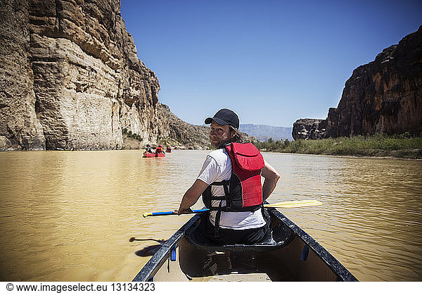 Portrait of smiling man with oar sitting in boat on river at Big Bend National Park