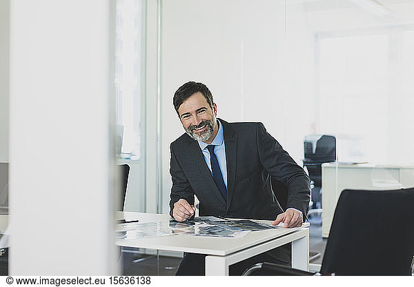 Portrait of smiling mature businessman sitting at desk in office