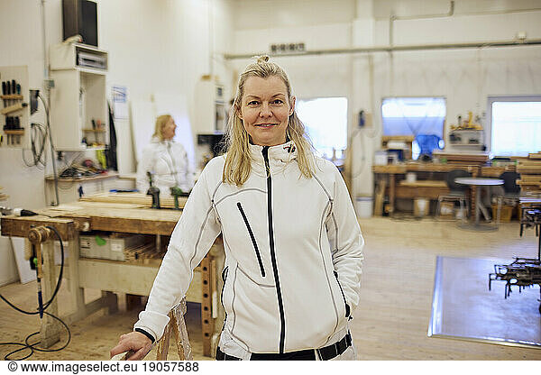 Portrait of smiling mature carpenter standing in workshop