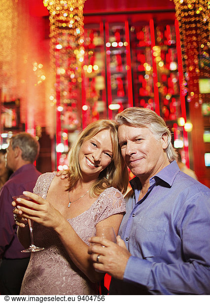 Portrait of smiling mature couple in bar  man in background
