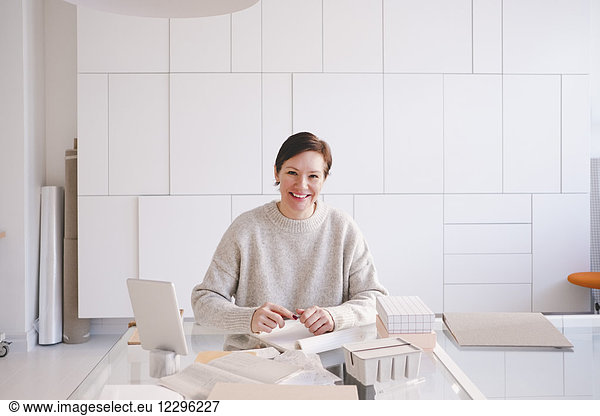 Portrait of smiling mature entrepreneur sitting at desk in upholstery store