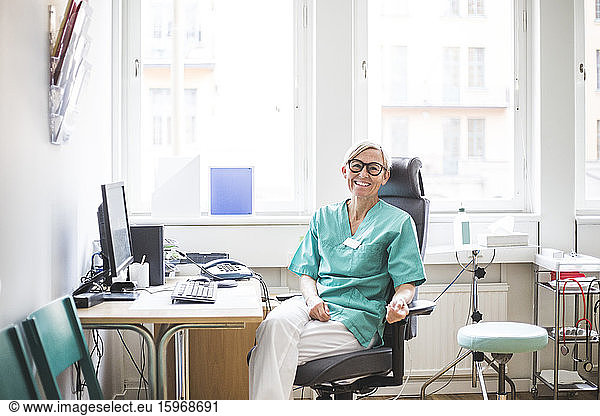Portrait of smiling mature female doctor sitting in clinic