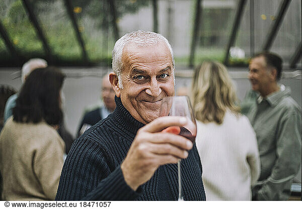 Portrait of smiling mature man holding wineglass at dinner party