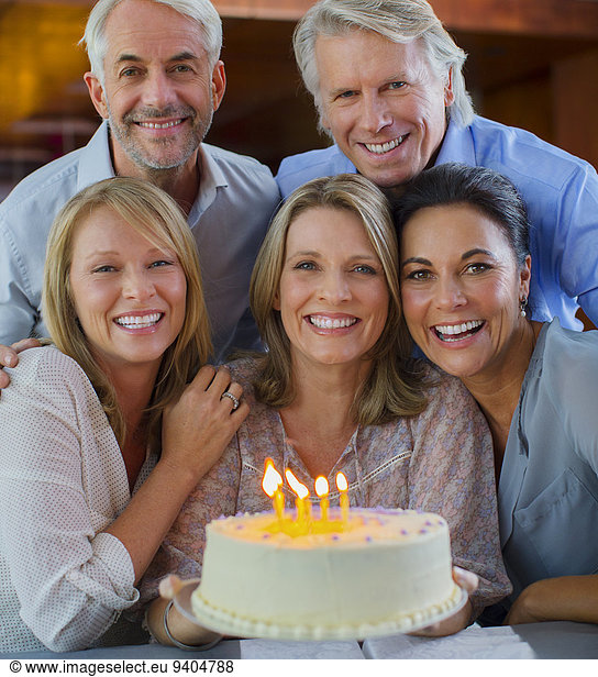 Portrait of smiling mature men and women with birthday cake