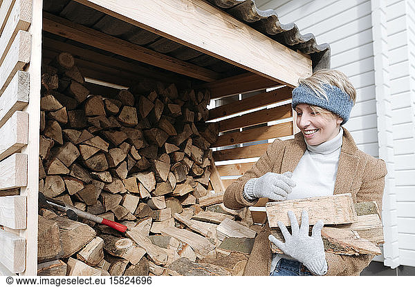 Portrait of smiling mature woman carrying firewood