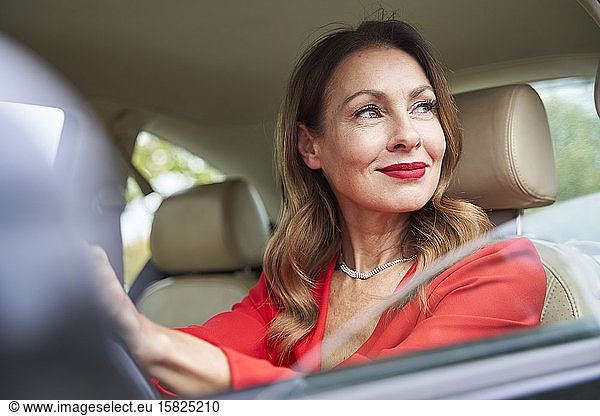 Portrait of smiling mature woman looking out of car window