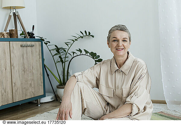 Portrait of smiling mature woman sitting on the floor at home