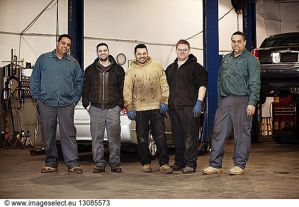 Portrait of smiling mechanics standing at auto repair shop