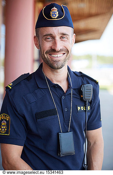 Portrait of smiling mid adult policeman standing outside police station