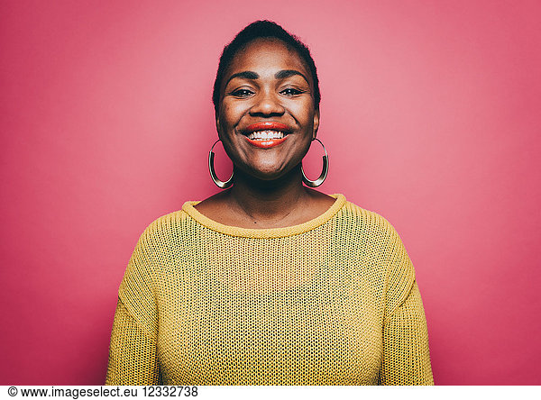 Portrait of smiling mid adult woman against pink background
