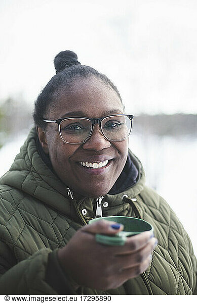 Portrait of smiling mid adult woman holding drink during winter