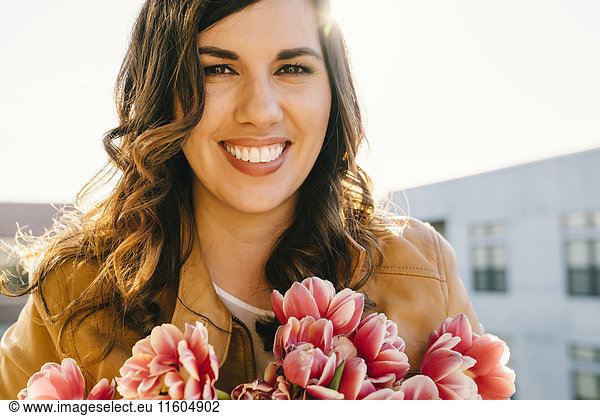 Portrait of smiling Mixed Race woman holding flowers