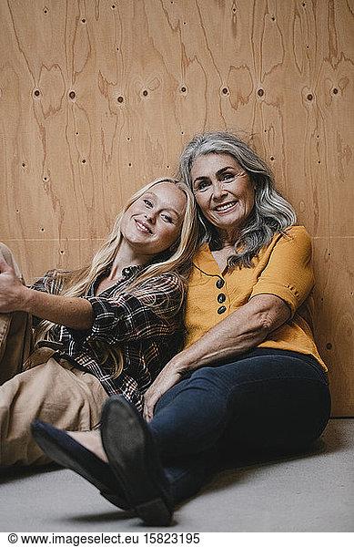 Portrait of smiling mother and adult daughter sitting on the floor