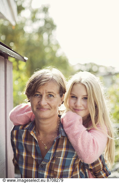 Portrait of smiling mother and daughter at yard