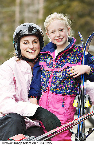 Portrait of smiling mother and daughter with skis