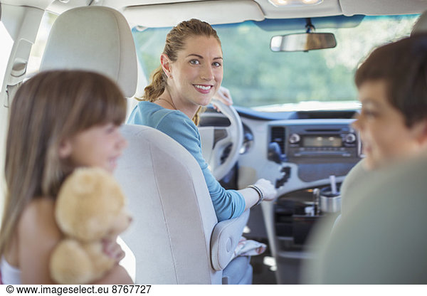 Portrait of smiling mother with family in car