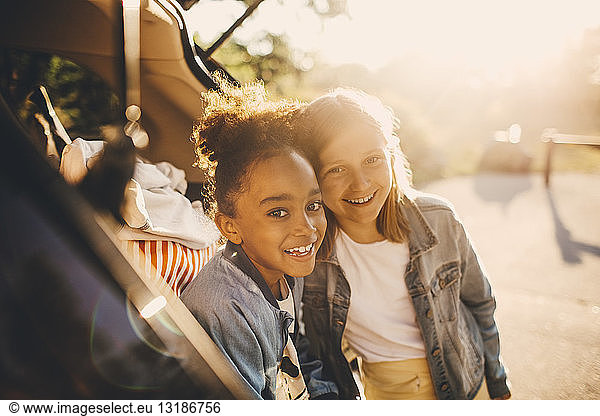 Portrait of smiling multi-ethnic girls in car trunk during picnic