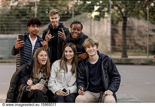 Portrait of smiling multi-ethnic male and female teenage friends at park in city