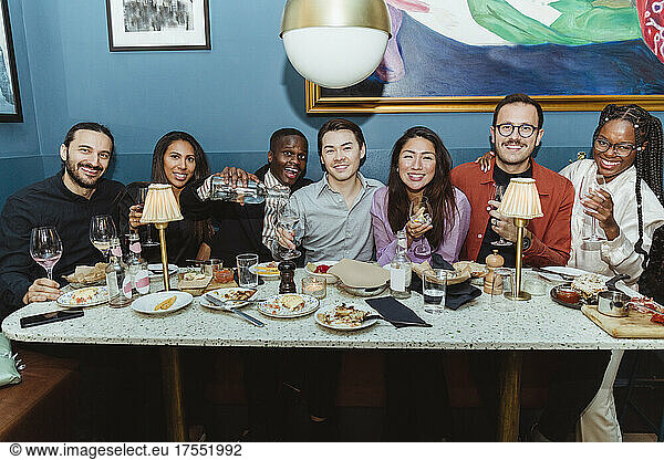 Portrait of smiling multiracial friends with wineglasses at restaurant
