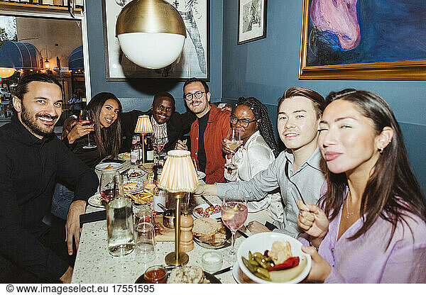 Portrait of smiling multiracial male and female friends during dinner party at bar