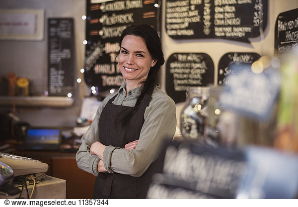 Portrait of smiling owner wearing apron standing at store