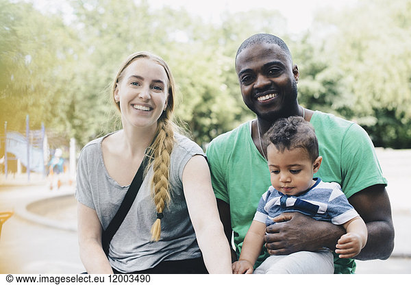 Portrait of smiling parents sitting with son at park